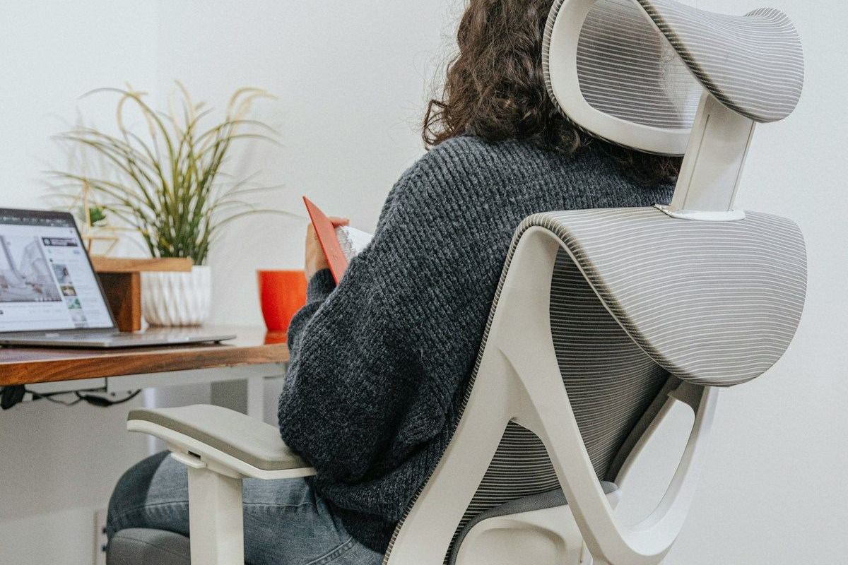Pessoa sentada em cadeira de escritório em frente ao computador